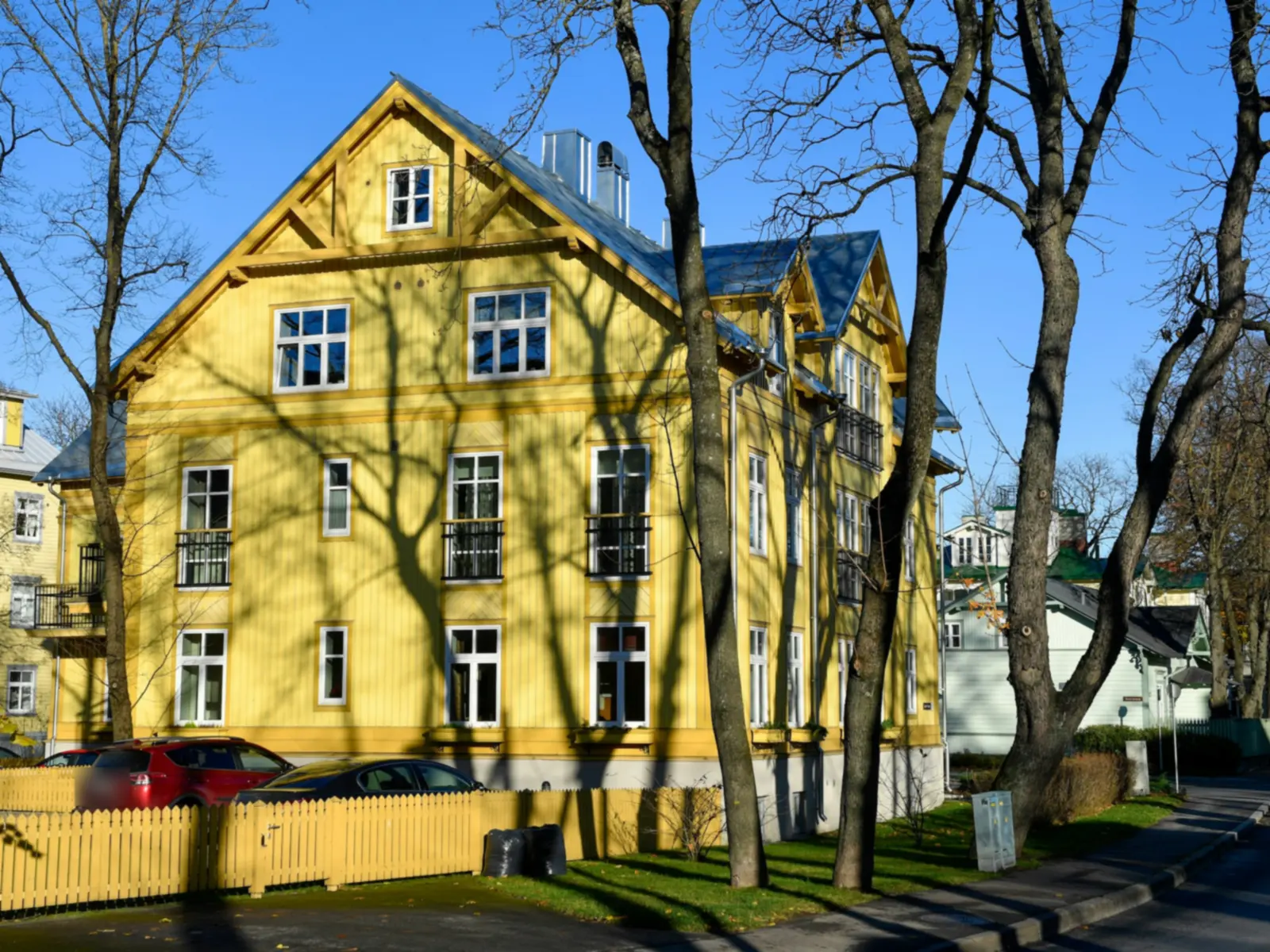 Gulmålad trävilla med vita fönster och gult staket